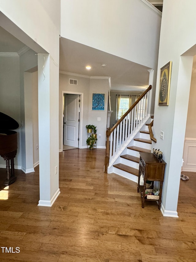 foyer featuring crown molding, stairs, visible vents, and wood finished floors