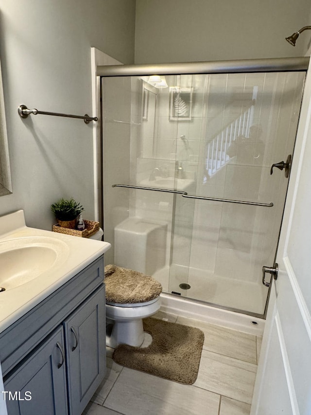 bathroom with toilet, a shower stall, vanity, and tile patterned floors