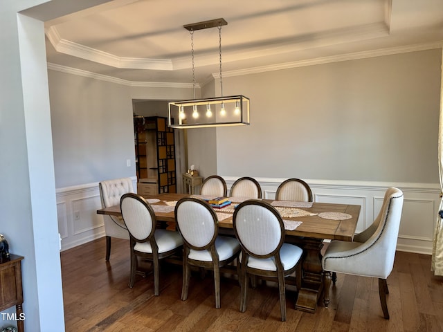 dining room featuring ornamental molding, wood finished floors, wainscoting, and a raised ceiling