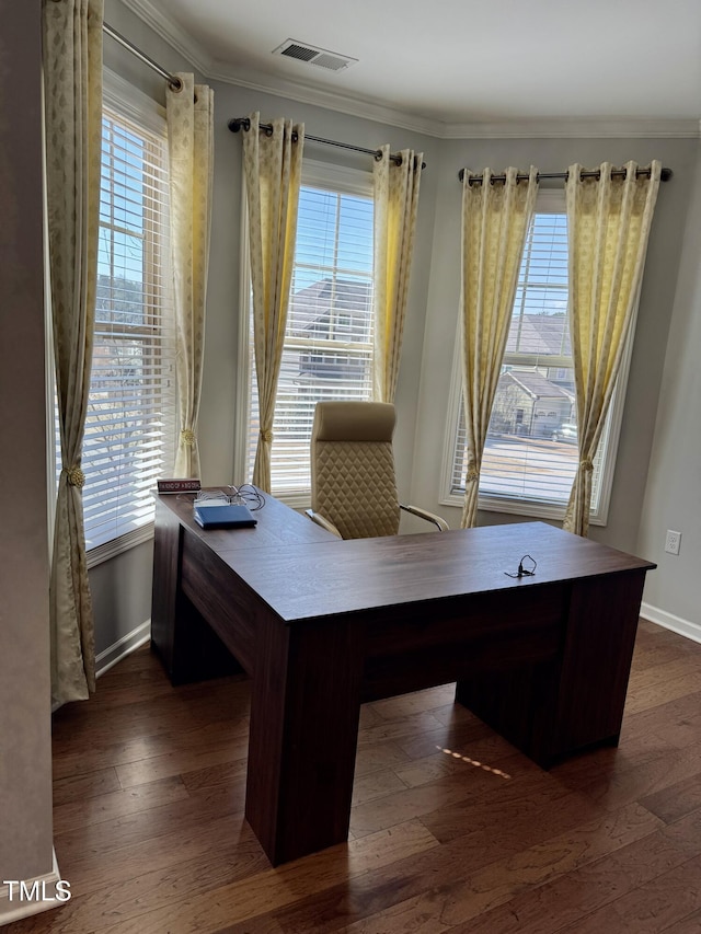 unfurnished office featuring dark wood-type flooring, visible vents, ornamental molding, and baseboards