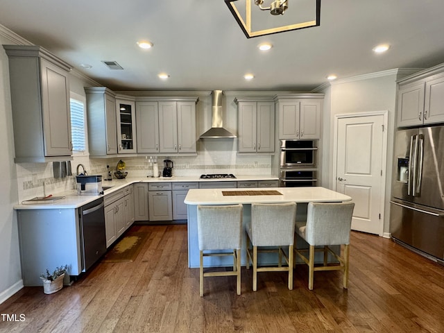 kitchen with visible vents, wall chimney exhaust hood, appliances with stainless steel finishes, gray cabinetry, and a sink