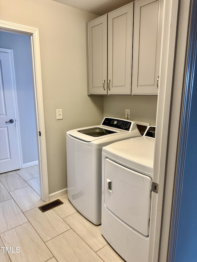 clothes washing area featuring cabinet space, visible vents, baseboards, wood tiled floor, and washing machine and dryer