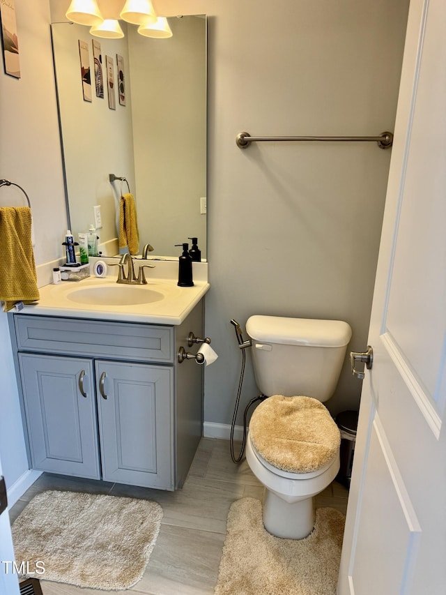 bathroom with toilet, wood finished floors, and vanity