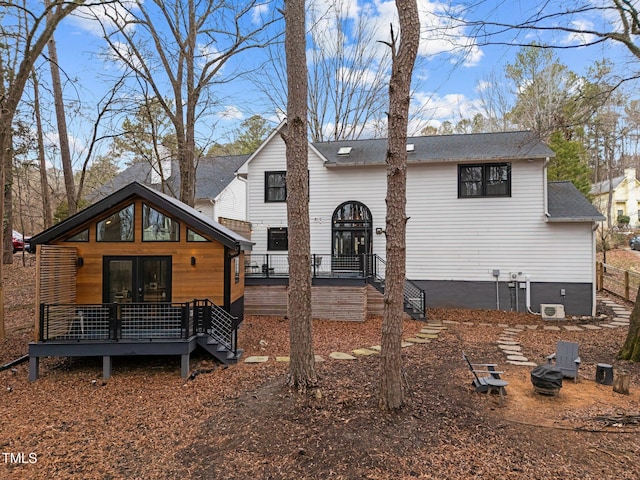 view of front of home featuring a deck, french doors, and a shingled roof