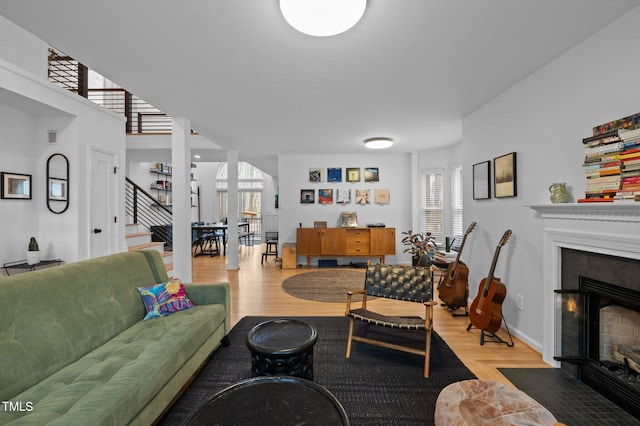 living room featuring a tiled fireplace, stairway, wood finished floors, and baseboards