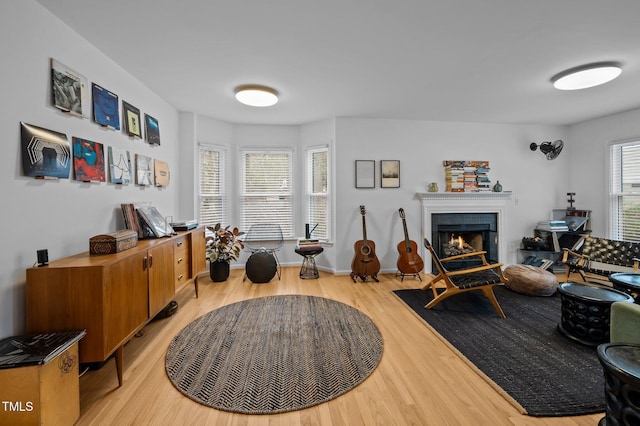 interior space featuring baseboards, light wood-style floors, and a lit fireplace