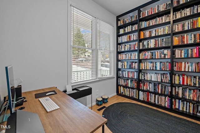 office space featuring wood finished floors and wall of books