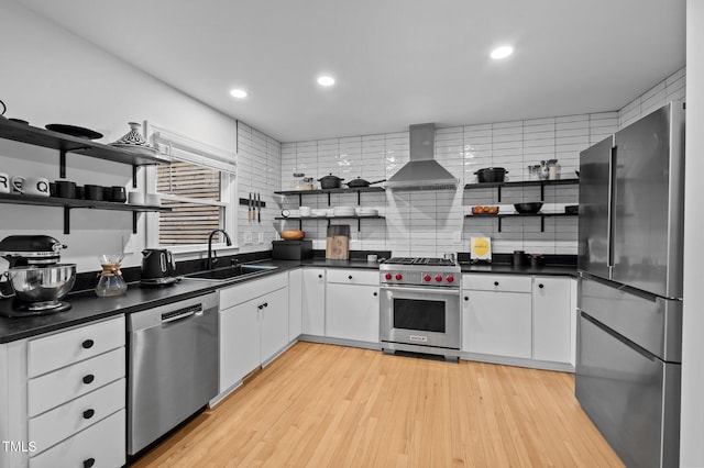 kitchen with open shelves, stainless steel appliances, a sink, and wall chimney range hood