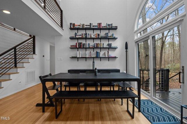 dining area with stairway, a high ceiling, light wood-style floors, and visible vents