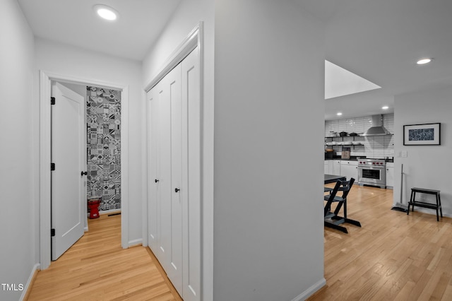 hallway with recessed lighting, light wood-type flooring, and baseboards