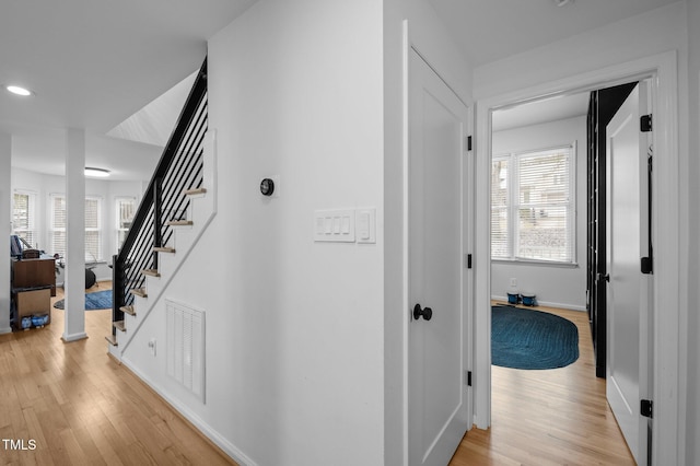 hallway featuring light wood-type flooring, visible vents, a wealth of natural light, and stairway