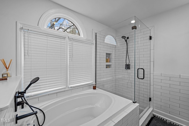 bathroom with tile walls, a bath, and a shower stall