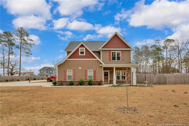 craftsman-style house featuring covered porch, a front lawn, and fence