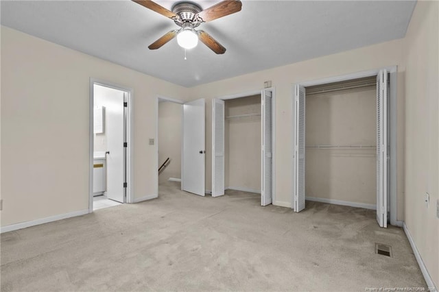 unfurnished bedroom featuring baseboards, visible vents, a ceiling fan, light colored carpet, and multiple closets