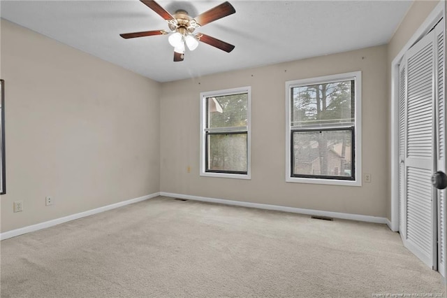 unfurnished bedroom with light carpet, visible vents, baseboards, ceiling fan, and a closet