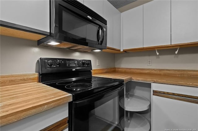 kitchen with black appliances, butcher block counters, and white cabinets