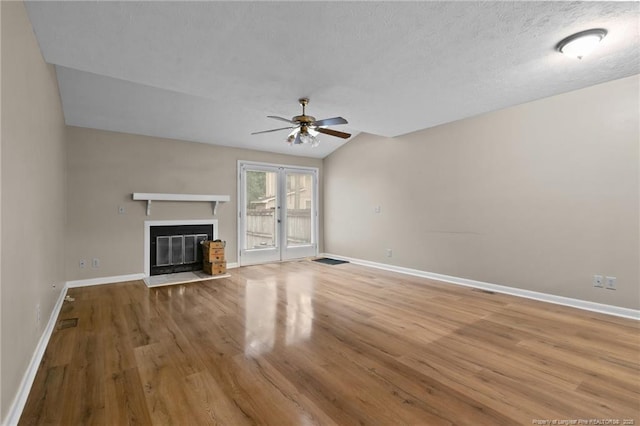 unfurnished living room with a glass covered fireplace, ceiling fan, baseboards, and wood finished floors