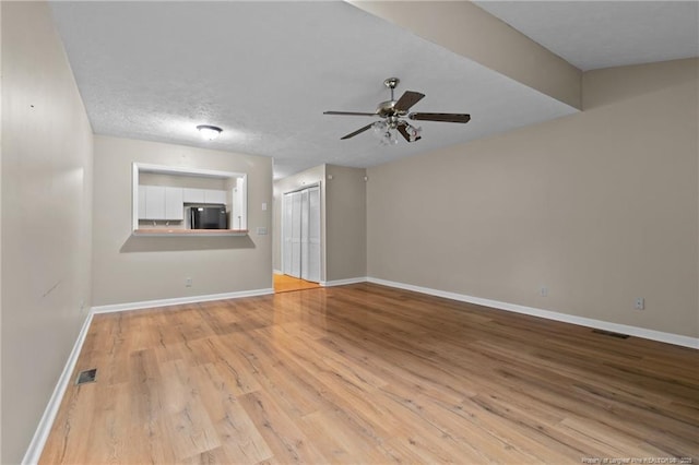 unfurnished room with a ceiling fan, visible vents, baseboards, and wood finished floors