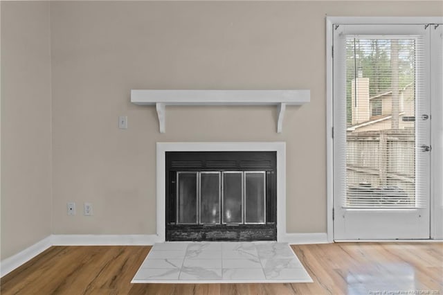 details featuring a fireplace with flush hearth, baseboards, and wood finished floors