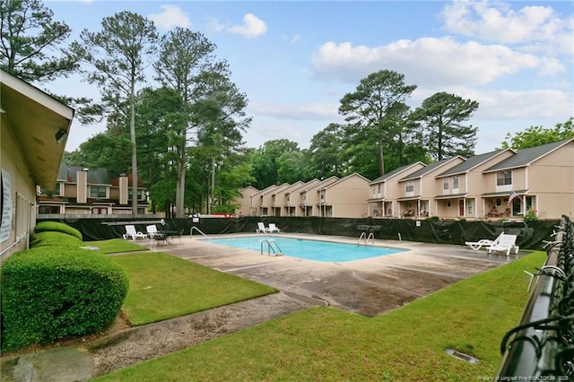 pool with a patio, a yard, fence, and a residential view