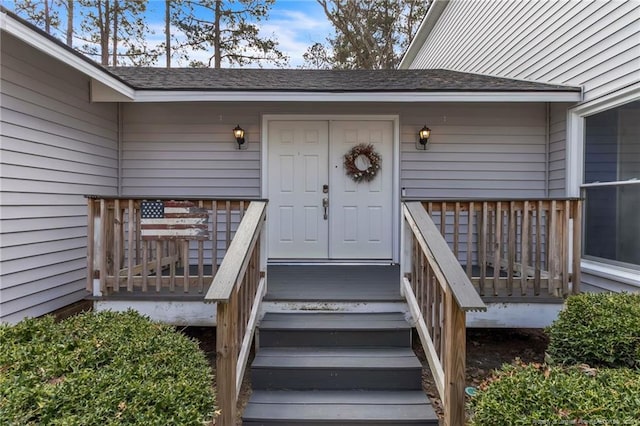 view of exterior entry with a shingled roof