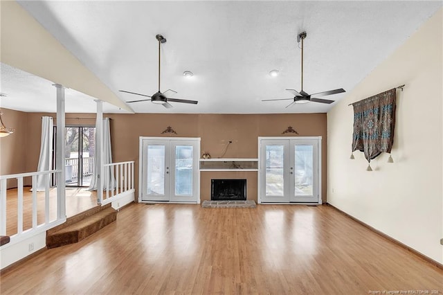 unfurnished living room featuring decorative columns, lofted ceiling, ceiling fan, wood finished floors, and french doors