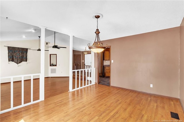 spare room with light wood-style floors, lofted ceiling, visible vents, and a ceiling fan