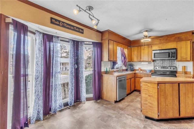 kitchen with visible vents, brown cabinetry, appliances with stainless steel finishes, light countertops, and a sink