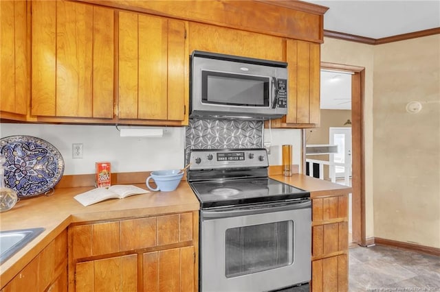 kitchen with appliances with stainless steel finishes, light countertops, and crown molding