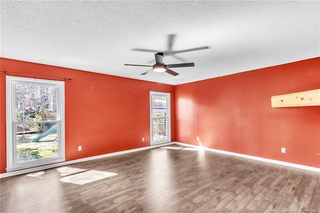 unfurnished room featuring a healthy amount of sunlight, a textured ceiling, and wood finished floors