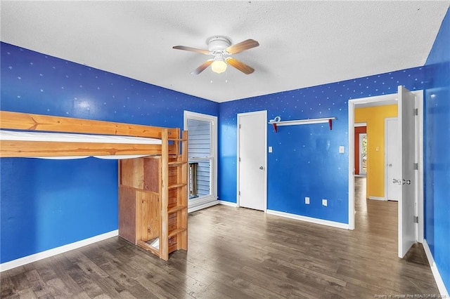 unfurnished bedroom featuring a textured ceiling, baseboards, and wood finished floors