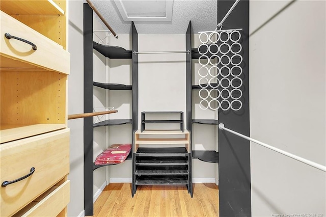 spacious closet with attic access and wood finished floors