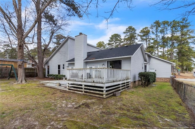 back of property with a deck, a yard, a chimney, and fence