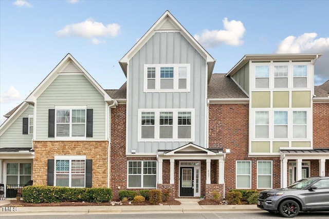 townhome / multi-family property with brick siding, board and batten siding, and a shingled roof