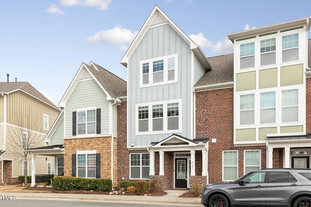 townhome / multi-family property featuring brick siding, board and batten siding, and roof with shingles