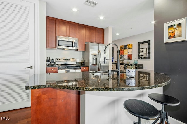 kitchen with recessed lighting, a sink, visible vents, appliances with stainless steel finishes, and a kitchen bar