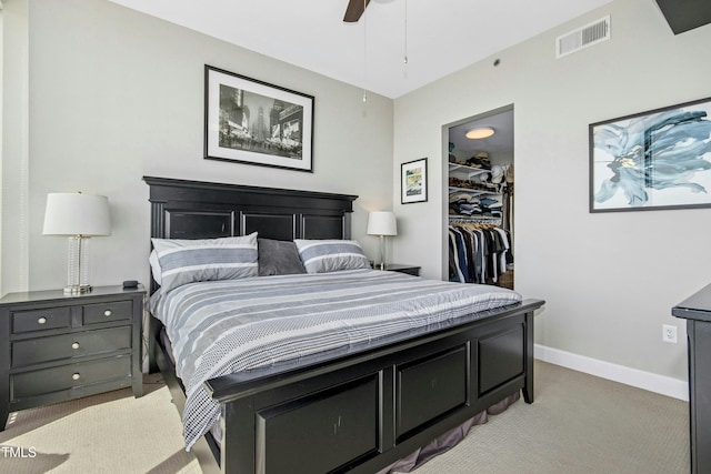 bedroom with a closet, light colored carpet, visible vents, a spacious closet, and baseboards