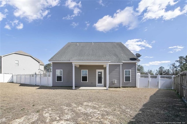 back of property with a patio, roof with shingles, a fenced backyard, and a gate