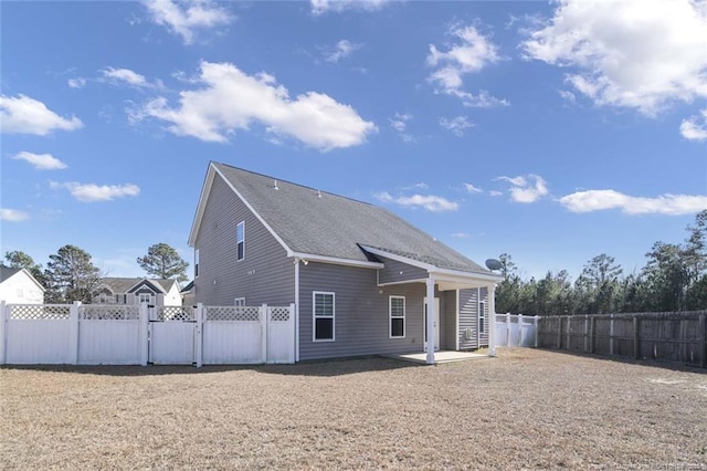 exterior space with a shingled roof, a patio area, a fenced backyard, and a gate