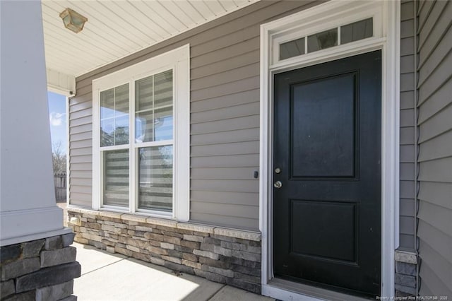 view of exterior entry featuring stone siding and a porch