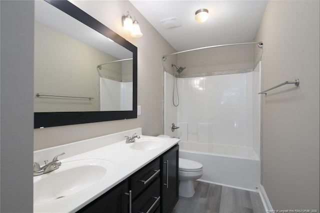 bathroom featuring double vanity, wood finished floors, a sink, and toilet