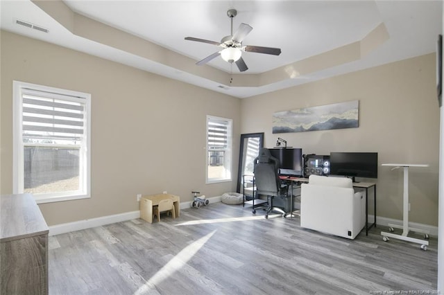 office area featuring wood finished floors, a raised ceiling, visible vents, and baseboards