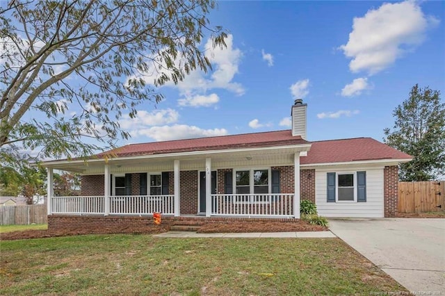 single story home featuring brick siding, a chimney, covered porch, fence, and a front yard