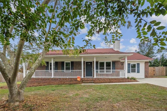 ranch-style house featuring a chimney, covered porch, fence, a front lawn, and brick siding