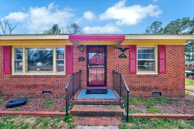 doorway to property featuring brick siding and crawl space