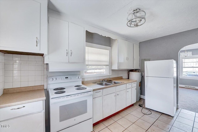 kitchen with under cabinet range hood, white appliances, a sink, white cabinets, and light countertops