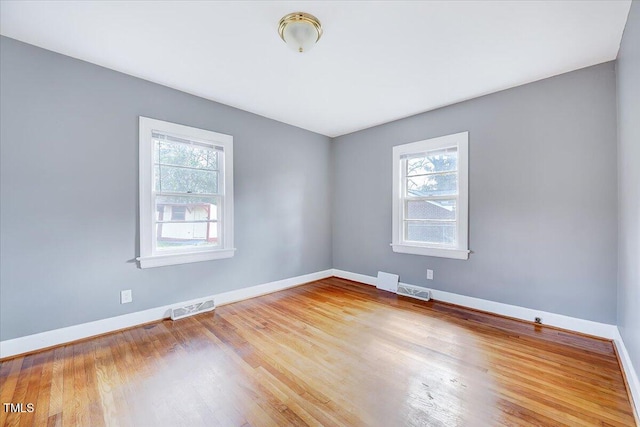 spare room featuring visible vents, baseboards, and wood finished floors