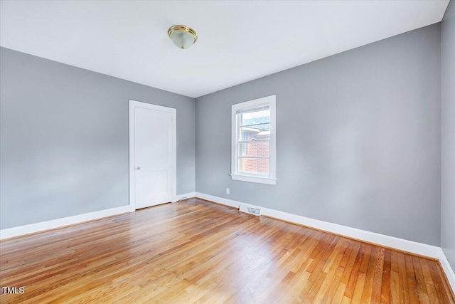 empty room featuring light wood-type flooring, visible vents, and baseboards