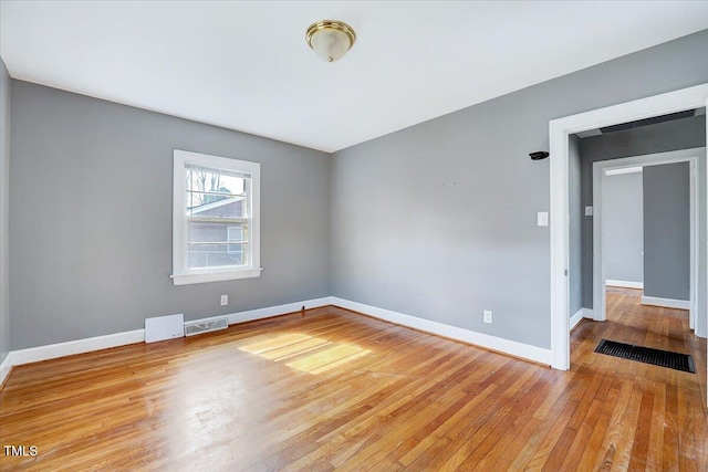 empty room with visible vents, baseboards, and wood finished floors