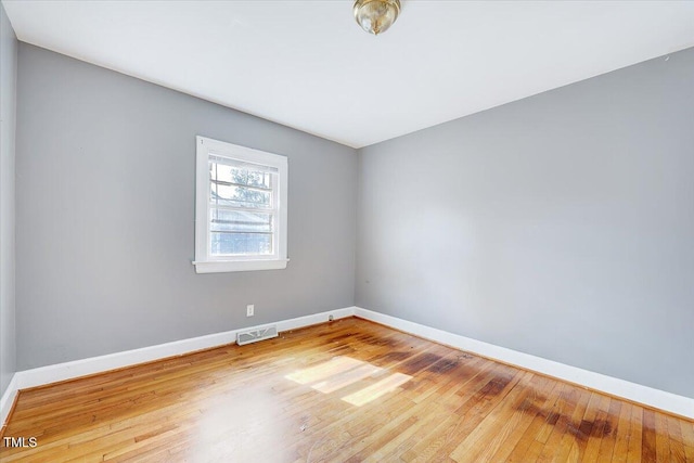 unfurnished room featuring visible vents, baseboards, and hardwood / wood-style flooring